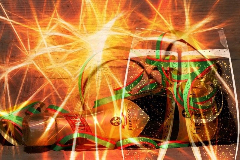 Feierliche Szene mit Champagner und Lichtspektakel Champagnerflasche und Gläser mit bunten Luftschlangen und strahlenartigen Lichteffekten.