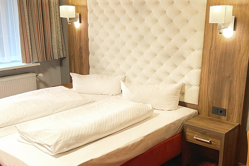 Gemütliches Hotelzimmer mit Doppelbett Modern eingerichtetes Hotelzimmer mit einem Doppelbett, gepolstertem Kopfteil und Nachtlampen.